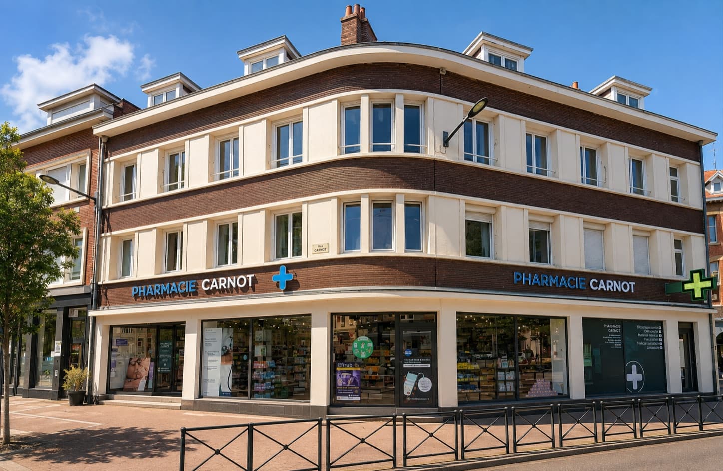 Immeuble d'angle de la Pharmacie Carnot, place Carnot à Douai : façade crème et panneaux de brique brune, deux enseignes « PHARMACIE CARNOT » avec croix, vitrines et grilles noires sur la place Carnot